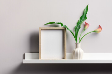 Portrait white picture frame mockup on shelf with flowers