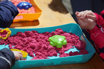 Kinetic sand sandbox with playing kids on children playground