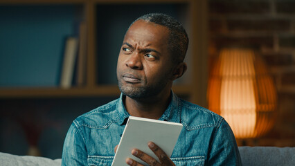 Pensive adult african american man indoors thinking deep in thoughts create strategy thoughtful...