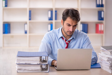 Young male employee and too much work in the office