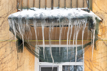 Large icicles hang from the balcony of the old house.