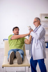 Obraz premium Young male patient visiting old male doctor in vaccination conce