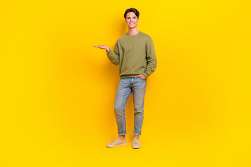 Full length photo of good looking man wear khaki clothes demonstrate empty space special offer isolated on yellow color background