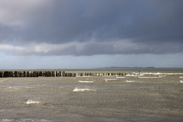 North Sea with wooden poles in a cloudy and windy day at Breskens