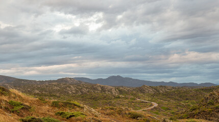 Panoramic view of the mountains of Cap de Creus a cloudy autumn day. There is a narrow winding road.
