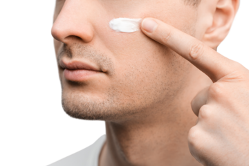 A portrait of a handsome man with a stubble in a white t-shirt, sample of a face cream on his cheek, applying with finger.