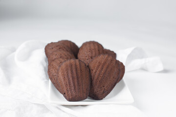 Chocolate madeleines on a ceramic plate, plain chocolate madeleine cake or cookies