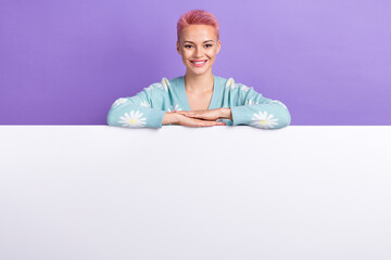 Portrait of pretty lovely nice girl with pink hairdo wear blue pullover lay hands on white poster isolated on violet color background