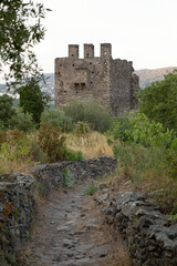Fototapeta na wymiar Back of the tower of the San Sebastian church on the mountain. Selva de Mar, Girona, Spain. Romantic style. The path is made of stone and has walls on the sides.