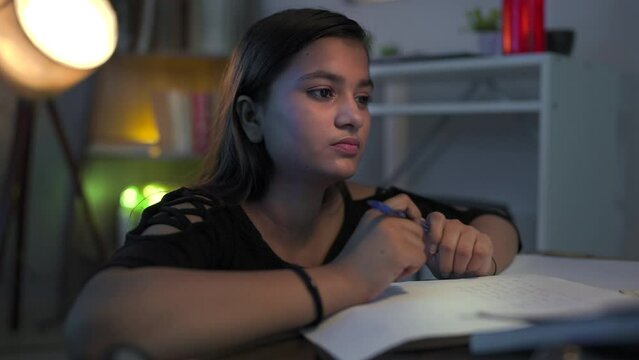 Anxious young Indian college girl with pen in hand feeling upset worried thinking for term exam, future, career while study. Troubled, stressed female revise hard question that doesn&rsquo;t know the answer