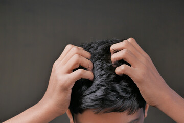 teenage boy Scratching Head Against black background .