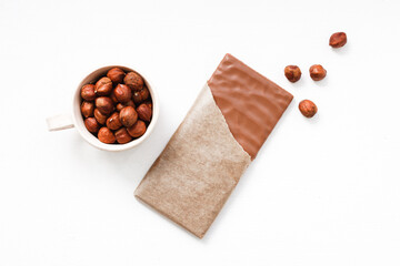 Chocolate bar with hazelnuts in a bowl on a white background