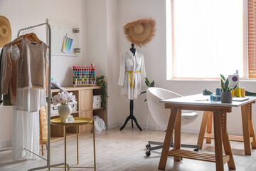 Interior of modern atelier with workplace, mannequin and clothes