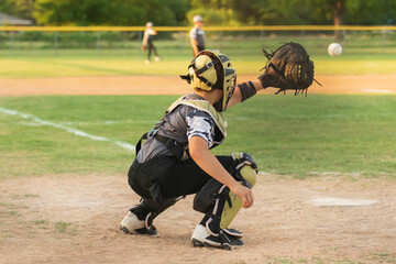 young boy playing catcher in a baseball game with blurred background 