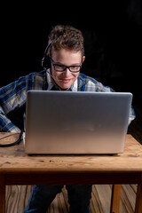 young boy with headphones at laptop working in front of black