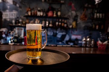 waiter hand and tray with Beer into glass on bar