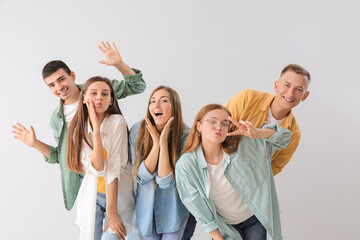 Group of happy friends gesturing on light background