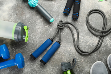 Skipping ropes with sports equipment, bottles and sneakers on dark background