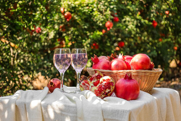 Table with pomegranates and glasses of water on farm, closeup