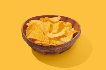 Potato chips in a bowl on yellow background