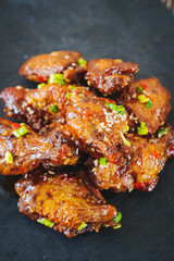 fried chicken with garlic and sesame in caramel on a black tray.