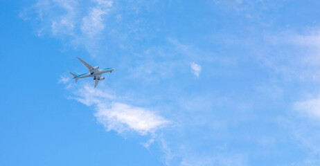 View of airplane flying in blue sky among white clouds. Banner, copy space. High quality photo
