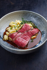 Traditional Italian chianina sliced roast beef with gnocchetti sardi pasta in spicy red wine sauce served as close-up in a Nordic design bowl with copy space