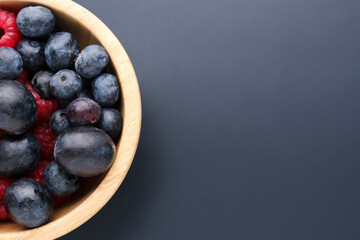 Wooden bowl of fresh berries on dark background