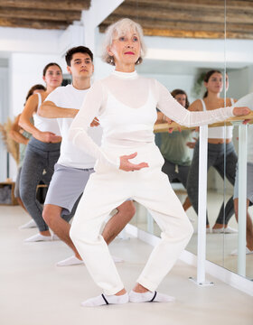 Women and men training in ballet class with other dancers