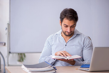 Young male teacher sitting in the classroom