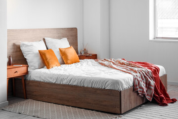 Interior of light bedroom with wooden tables and vases