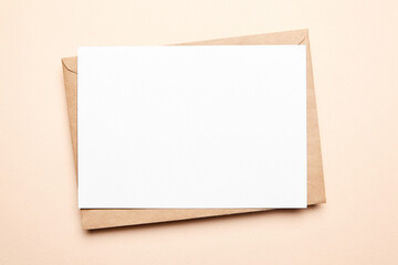 Greeting card mockup with envelop on beige background, top view, flat lay. Blank holiday card or flyer