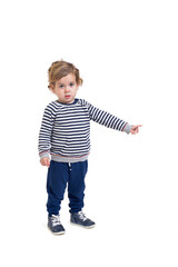 standing baby boy looking at camera and pointing finger to the side on white background