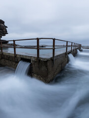 Long exposure view of water flowing out of North Curl Curl rock pool, Sydney, Australia.