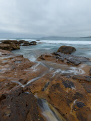 Fototapeta na wymiar Wave water flowing on the rocky coastline.