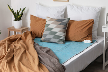 Bed with pillows and electric heating pad in bedroom © Pixel-Shot