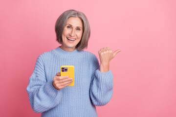 Closeup portrait photo of having fun funky retired influencer blogger woman direct finger empty space advert phone isolated on pink color background