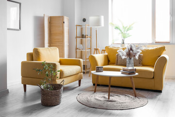 Interior of living room with yellow sofa, armchair and pampas grass in vase