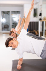 People exercising yoga poses in fitness center. Extended triangle pose