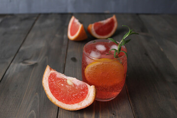 drink lemonade juice from red orange grapefruit in a glass with a sled and mint rosemary on a gray background with a place for text. Refreshing cold summer drinks from the heat