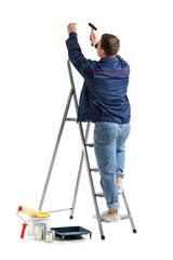 Young man with ladder nailing on white background