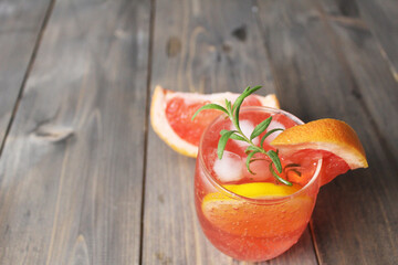 drink lemonade juice from red orange grapefruit in a glass with a sled and mint rosemary on a gray background with a place for text. Refreshing cold summer drinks from the heat