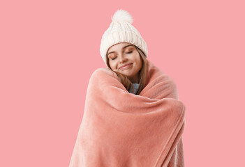 Frozen young woman in warm hat with plaid on pink background