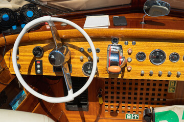 Authentic vintage design of the interior and controls in the cockpit of a sea boat on a sunny day. Real white steering wheel of a sea cab boat in Venice. Voyages and adventures at sea © Oleksandr Bochkala