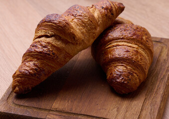 Baked crispy croissant on a wooden board, breakfast