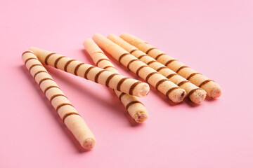 Tasty wafer rolls on pink background