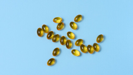 Yellow capsules with fish oil on a blue background, top view