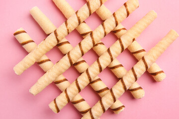 Tasty wafer rolls on pink background