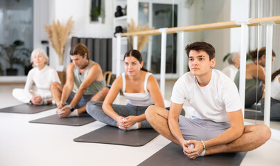 Fototapeta na wymiar Active vigorous man performs exercises on a pilates mat in the hall of a modern fitness studio.
