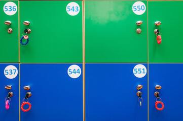 Blue and green lockers with keys and numbers in a public locker room in a children's entertainment center or in a clothing store. Warehouse in a supermarket.